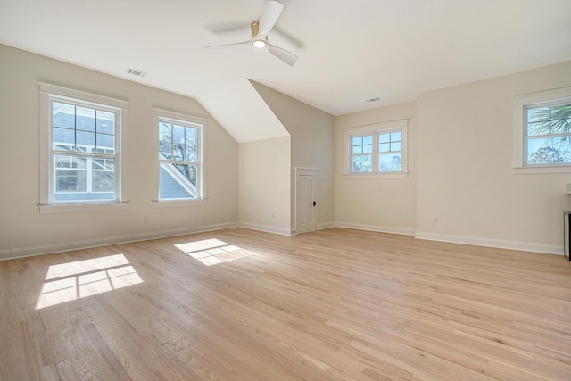 additional living space featuring ceiling fan, lofted ceiling, a wealth of natural light, and light wood-type flooring