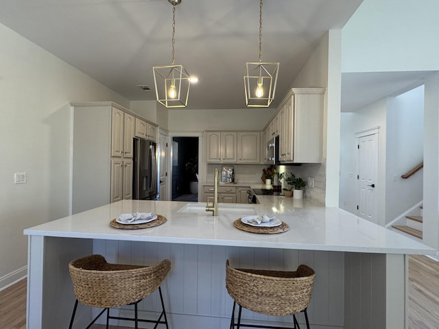 kitchen featuring sink, a breakfast bar, stainless steel appliances, decorative backsplash, and kitchen peninsula