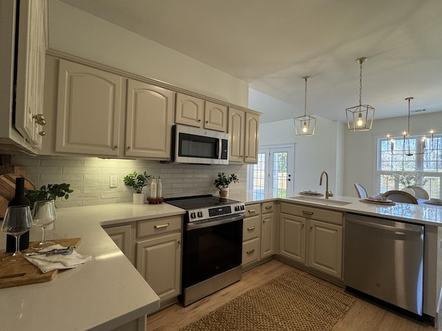 kitchen featuring sink, decorative light fixtures, stainless steel appliances, and kitchen peninsula