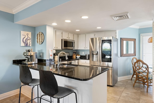 kitchen with white cabinetry, ornamental molding, stainless steel appliances, and kitchen peninsula