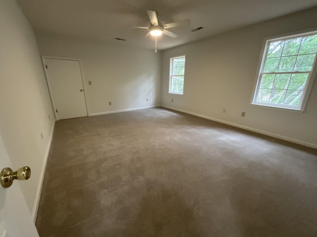 spare room with carpet floors, visible vents, and baseboards