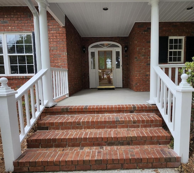 entrance to property with covered porch and brick siding