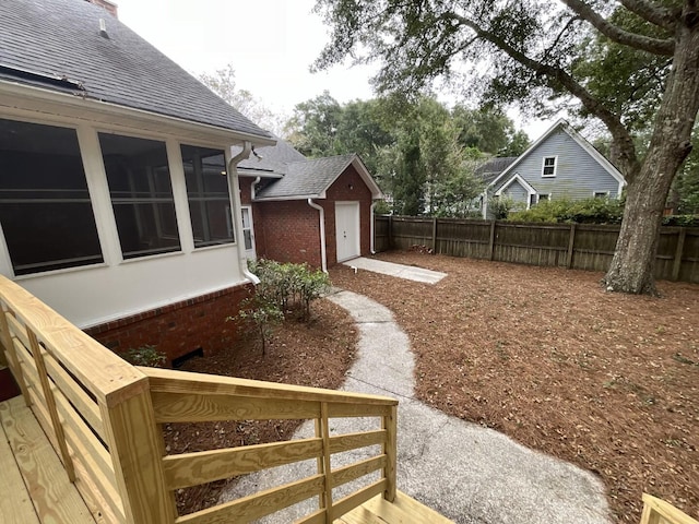 view of yard with a garage, a sunroom, and fence