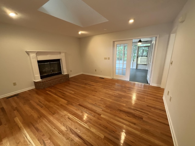 unfurnished living room featuring a fireplace, baseboards, and wood finished floors