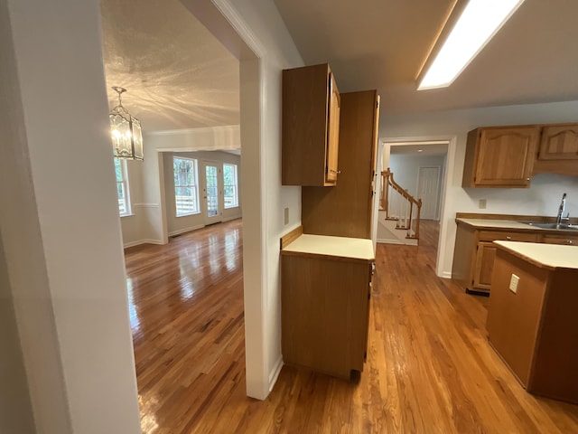 kitchen with a notable chandelier, a sink, baseboards, light wood-style floors, and light countertops