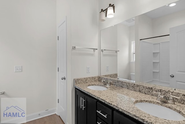 333 Grayson Ave, Hinesville, GA 31313 - bathroom featuring toilet, double vanity, wood finished floors, baseboards, and a shower