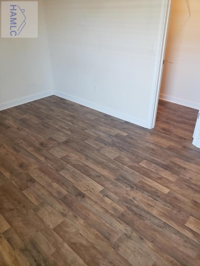 empty room with dark wood-style floors and baseboards