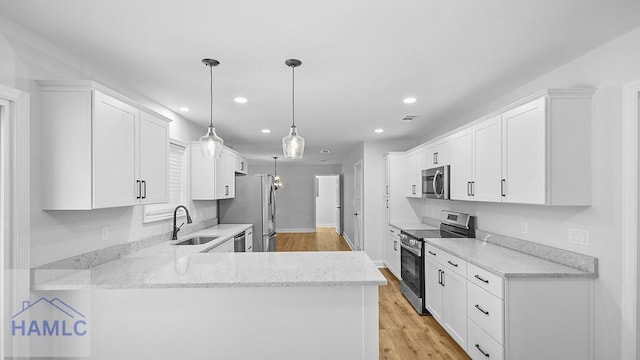 kitchen with kitchen peninsula, stainless steel appliances, sink, white cabinets, and hanging light fixtures