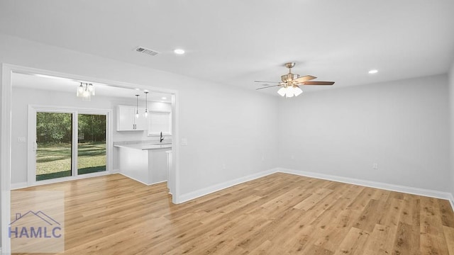 unfurnished room featuring ceiling fan with notable chandelier, light hardwood / wood-style floors, and sink