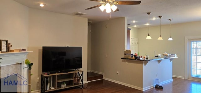 interior space featuring hanging light fixtures, ceiling fan, dark wood-type flooring, and a fireplace