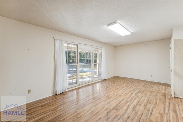 unfurnished room with a textured ceiling and light wood-type flooring