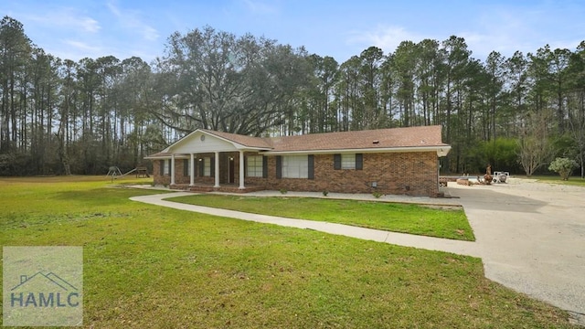 view of front facade with concrete driveway, brick siding, a front lawn, and covered porch