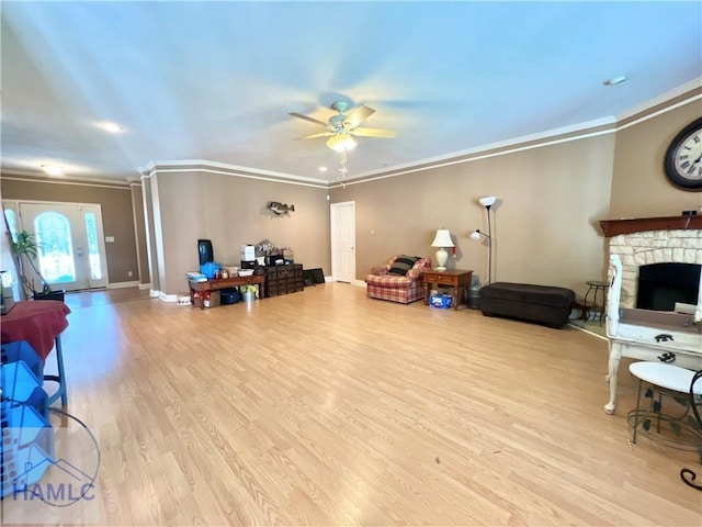 living room featuring crown molding, a fireplace, light hardwood / wood-style floors, and ceiling fan