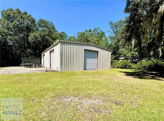 view of outbuilding featuring a garage, a trampoline, and a lawn