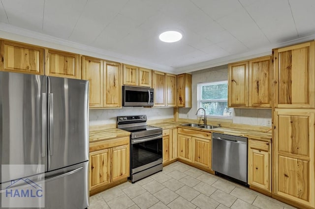 kitchen with light tile patterned flooring, stainless steel appliances, ornamental molding, and sink