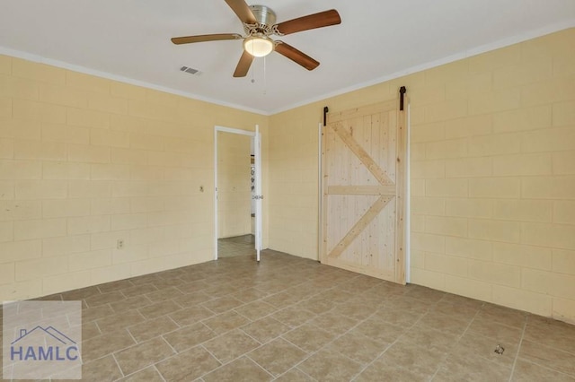 spare room featuring a barn door, ceiling fan, and ornamental molding