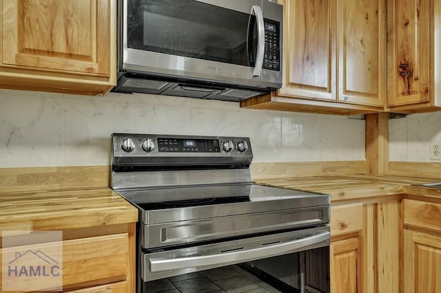 kitchen featuring tile patterned floors, butcher block counters, and stainless steel appliances