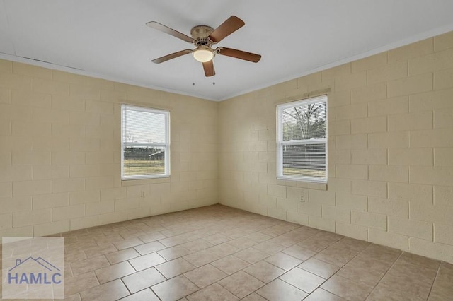 empty room with a wealth of natural light, ceiling fan, and light tile patterned floors