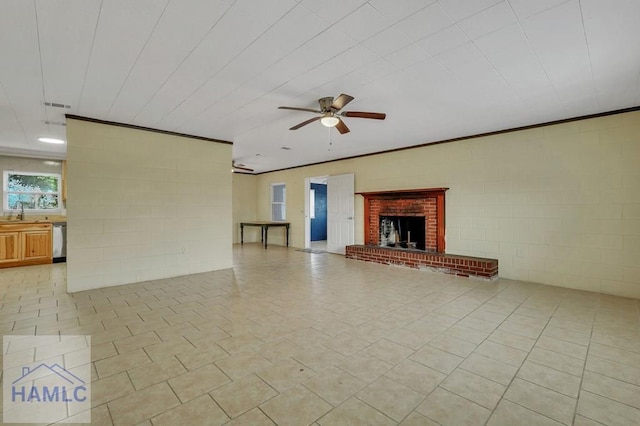 unfurnished living room featuring ceiling fan, sink, and a brick fireplace