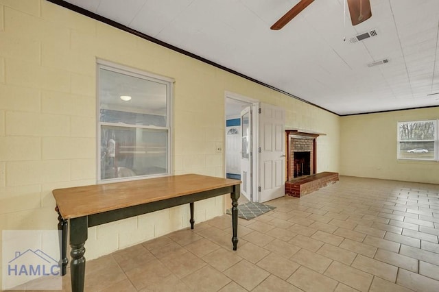 interior space featuring a fireplace, light tile patterned floors, ceiling fan, and crown molding