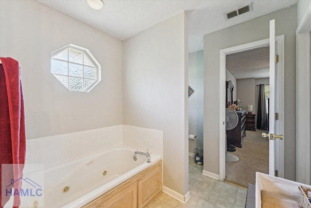 bathroom featuring a jetted tub, baseboards, a textured ceiling, and visible vents