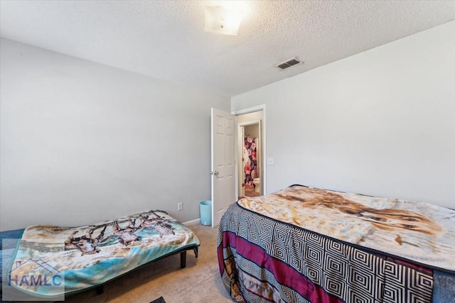 bedroom featuring visible vents, a textured ceiling, and light colored carpet