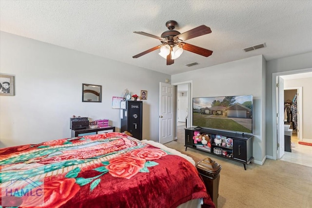bedroom featuring visible vents, a ceiling fan, a textured ceiling, and light carpet