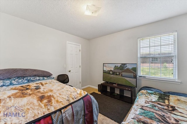 carpeted bedroom featuring a textured ceiling and baseboards