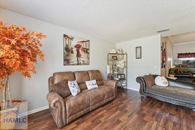 living room with baseboards, a textured ceiling, wood finished floors, and visible vents