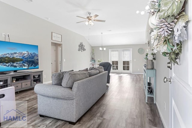 living area featuring wood finished floors, ceiling fan with notable chandelier, baseboards, and vaulted ceiling