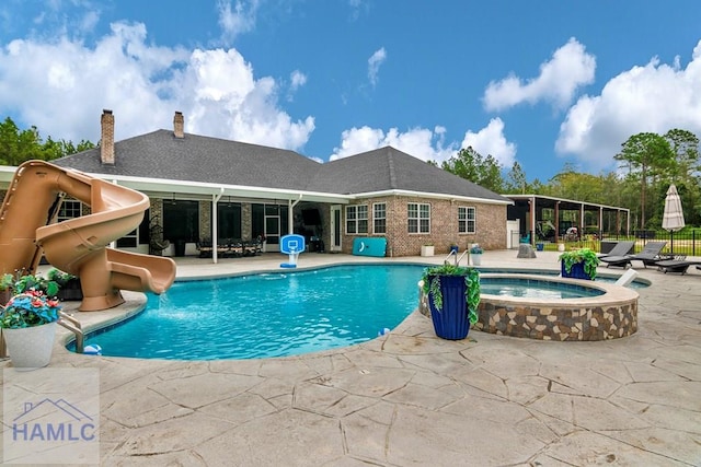 view of swimming pool featuring a patio area, an in ground hot tub, and a water slide