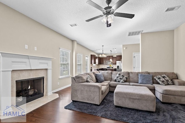 557 Archie Way NE, Ludowici, GA 31316 - living area with dark wood-type flooring, ceiling fan, a textured ceiling, a tile fireplace, and baseboards