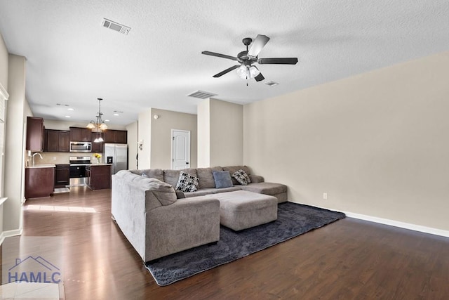 557 Archie Way NE, Ludowici, GA 31316 - living area with a chandelier, ceiling fan, dark wood-style flooring, baseboards, and a textured ceiling