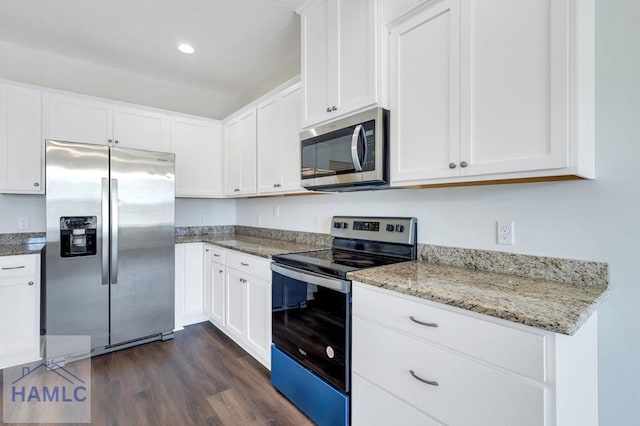 kitchen with dark hardwood / wood-style flooring, light stone counters, white cabinets, and appliances with stainless steel finishes