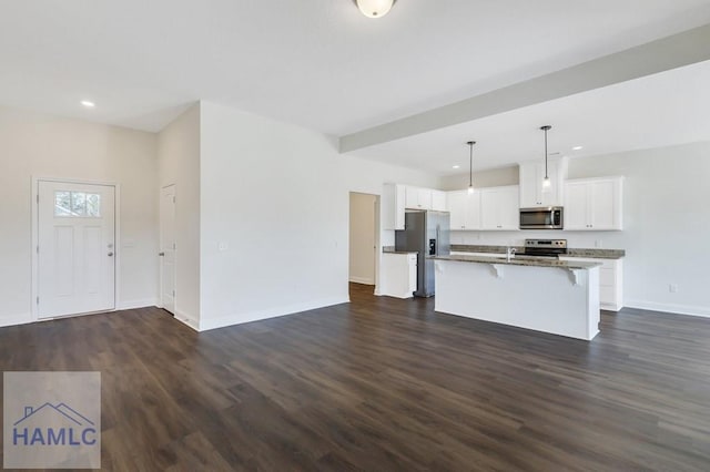 kitchen with an island with sink, white cabinetry, a kitchen breakfast bar, hanging light fixtures, and stainless steel appliances