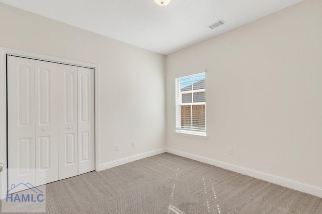 unfurnished bedroom with light colored carpet and a closet