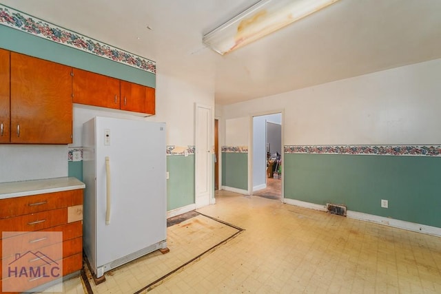 153 Drennon Dr, Jesup, GA 31545 - kitchen with freestanding refrigerator, light flooring, baseboards, light countertops, and brown cabinetry