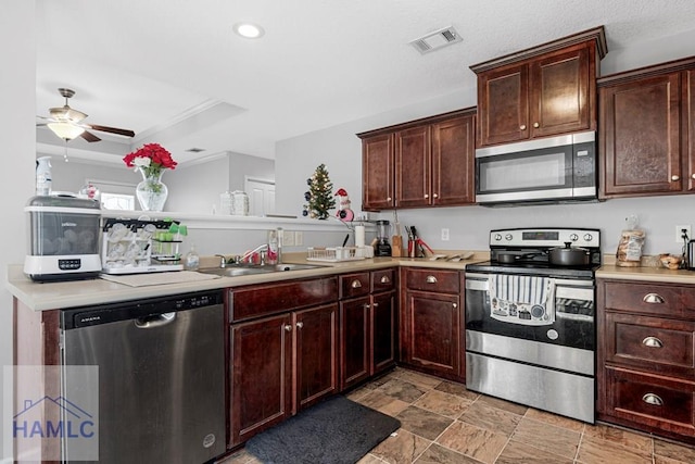 kitchen with appliances with stainless steel finishes, ceiling fan, sink, and a tray ceiling