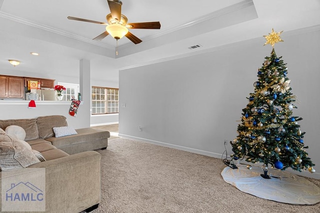 carpeted living room featuring ceiling fan, a tray ceiling, and crown molding