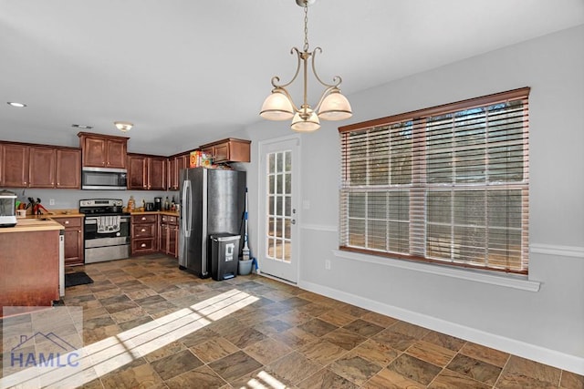 kitchen featuring plenty of natural light, stainless steel appliances, a notable chandelier, and hanging light fixtures