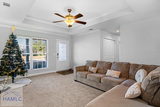 carpeted living room featuring a raised ceiling, ceiling fan, and ornamental molding