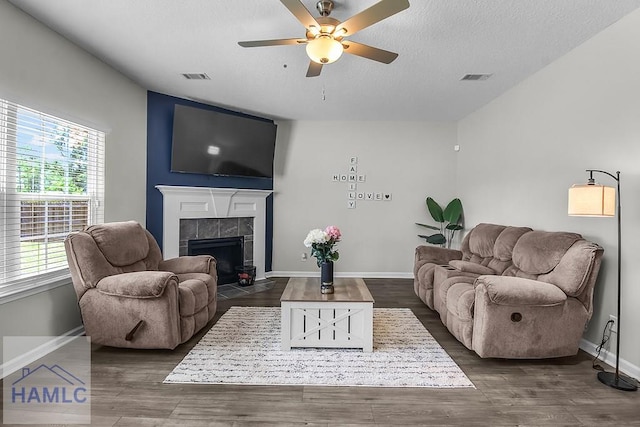 26 Sunflower Cir, Ludowici, GA 31316 - living area featuring ceiling fan, a textured ceiling, baseboards, a tile fireplace, and dark wood-style floors