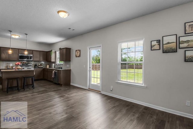 26 Sunflower Cir, Ludowici, GA 31316 - kitchen featuring appliances with stainless steel finishes, dark wood finished floors, a breakfast bar, baseboards, and tasteful backsplash