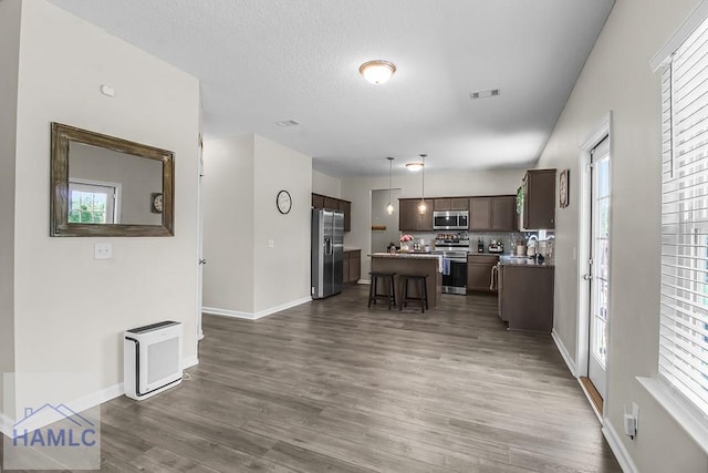 26 Sunflower Cir, Ludowici, GA 31316 - kitchen featuring appliances with stainless steel finishes, a center island, a breakfast bar, wood finished floors, and dark brown cabinetry