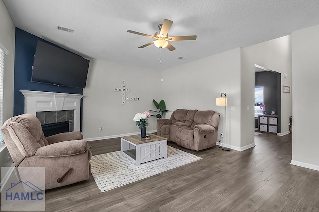 26 Sunflower Cir, Ludowici, GA 31316 - living area with a ceiling fan, a tiled fireplace, dark wood-style flooring, baseboards, and a textured ceiling
