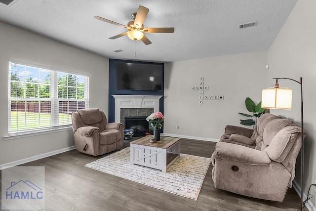 26 Sunflower Cir, Ludowici, GA 31316 - living area with a textured ceiling, a tiled fireplace, a ceiling fan, baseboards, and dark wood-style floors