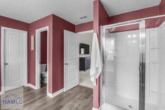 26 Sunflower Cir, Ludowici, GA 31316 - full bathroom featuring wood finished floors, toilet, a stall shower, baseboards, and a textured ceiling