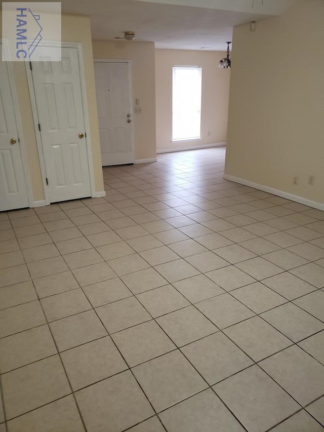 unfurnished room featuring light tile patterned floors and a notable chandelier