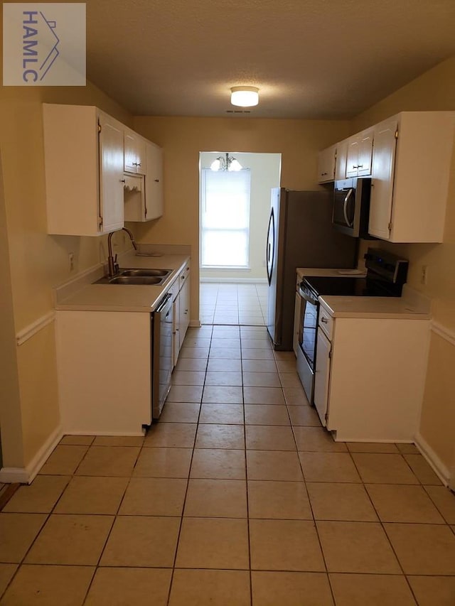 kitchen with light tile patterned floors, stainless steel appliances, white cabinetry, and sink