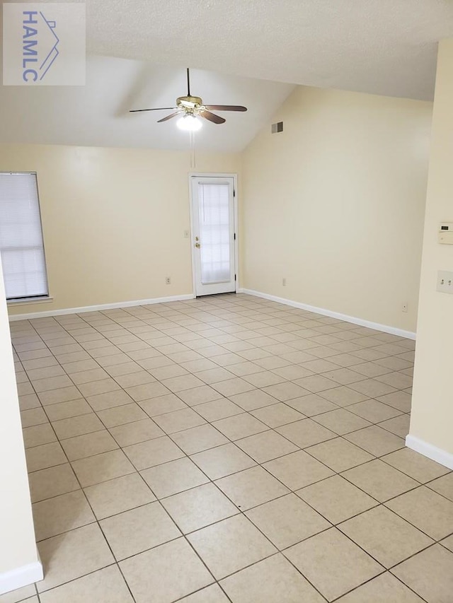 spare room featuring a textured ceiling, ceiling fan, lofted ceiling, and light tile patterned flooring